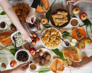 Festive easter meal on a wooden table with home baking. Meeting with friends who have healthy, natural foods. Flat lay of a table with people hands.