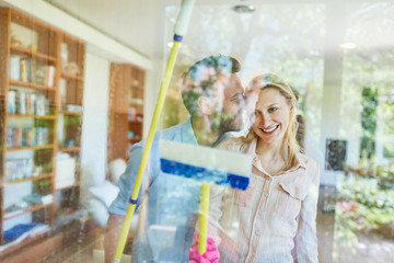 Happy young couple brushing glass by the window