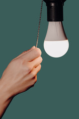 woman's hand turning off the light of a light bulb