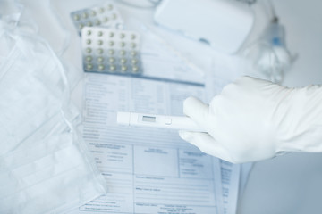 hand in gloves with a virus test on a background of a desktop in a hospital. coronovirus test in the laboratory, light background