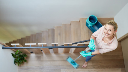 Woman cleaning house hallway in staircase
