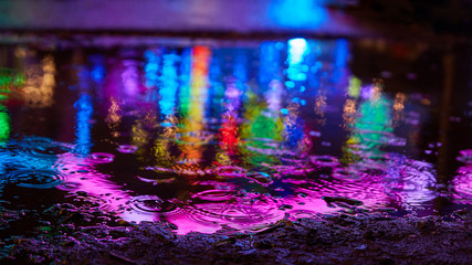 Reflection of colorful lights in puddle when it rains