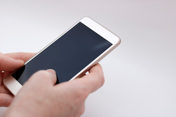 The guy holds a smartphone in his hand on a white background. The man uses the phone. Remote work through a mobile device.
