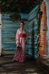 beautiful girl in a pink kimono with a cage with a bird