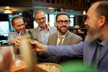 Group of friends toasting with beer and celebrating the beginning of the weekends in the bar