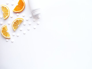 scattered vitamin pills and bottle with lemon orange on white background. Copyspace, flat lay. Concept boost immune system, medicine and tablets.