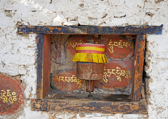 Small colorful prayer wheel, white wall, Bumthang Bhutan 