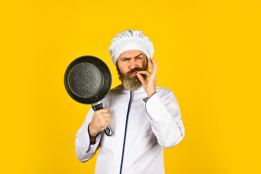 Professional kitchenware. Frying meal. Healthy food. Bearded chef preparing breakfast. Nonstick pan for frying. Enameled cooking vessels. Man hold pan. Nonstick cookware. Frying without oil