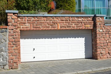 Garage mit Automatik-Rolltor integriert in die Buntsandstein-Grundstücksmauer mit...