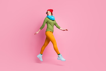 Fototapeta na wymiar Full length photo of cheerful cute youth girl jump walk go look copyspace feel dreamy about spring discounts wear trousers sweater isolated over pink color background
