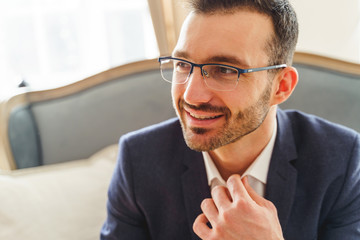 Pleased short-haired elegant young man wearing spectacles