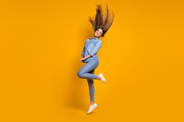 Fototapeta na wymiar Full length profile photo of pretty lady jumping high up hairdo flying good mood weekend wear casual jeans denim outfit white shoes isolated yellow color background