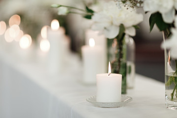 Table setting at wedding reception. Floral compositions with beautiful flowers and greenery, candles on decorated table. Coziness and style. Modern event design. selective focus.