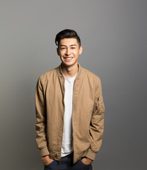 Obraz premium Portrait of smiling young man standing against gray background