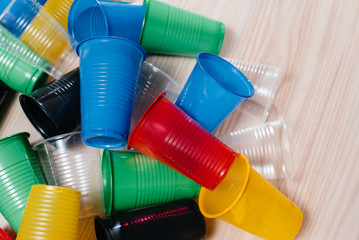 A large pile of multicolored plastic cups scattered on the floor. Pollution of the environment by human waste