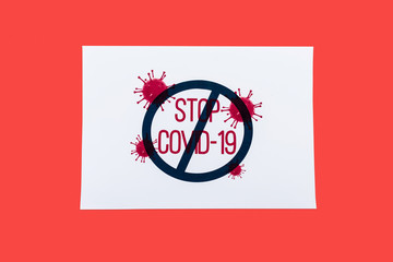 top view of paper with stop covid-19 lettering isolated on red