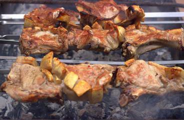 Beautifully fried pork steaks on skewers smoke on hot coals