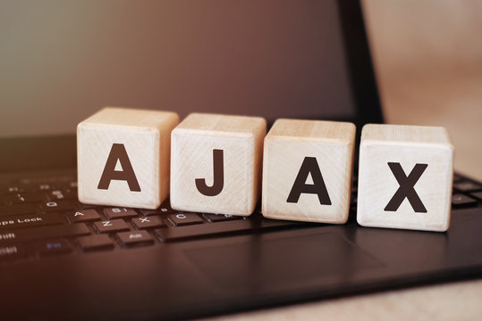AJAX - Programming text on a wooden cube on a black laptop