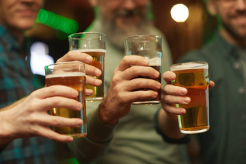 Close-up of group of men holding glasses of beer and celebrating the holiday