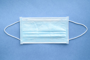 Medical surgical mask on a blue background. Face mask to protect the mouth and nose. Top view....