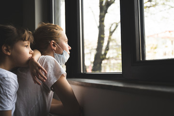 woman and daughter with protection medical face mask by the window
