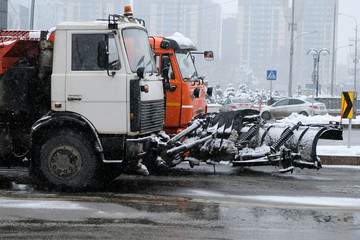 Snow removing equipement in the street in blizzard. Trucks with snowplow on winter city streets.
