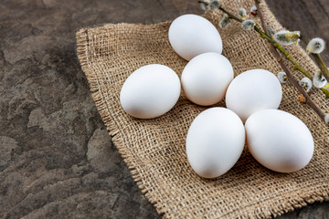 Fresh organic farm eggs lie on burlap, on a stone slab, close-up, selective focus, shallow depth of field. Concept, healthy food, spring religious holidays.