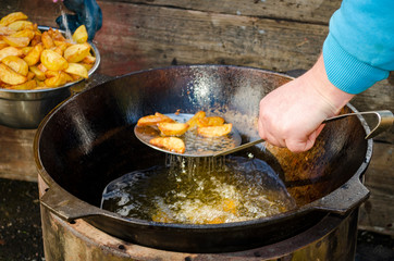 hands establish fried potatoes in a cauldron steam goes and boils oil