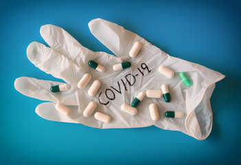 Sanitary gloves with the word covid 19 and pills on blue background