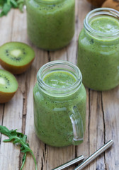 Green drink smoothie with kiwi, spinach and rucola in a jar on a wooden background in rustic style