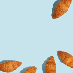 Fotobehang Appetizing crunchy croissants on a blue background. A look from above © Max