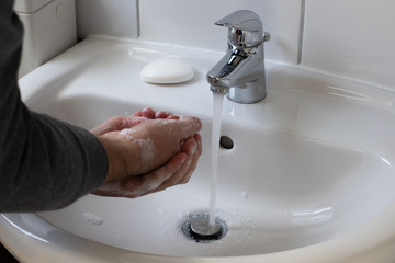 Detail of a Young male washing his Hands with Soap under running water in order to reduce infection Risk during corona Virus pandemic