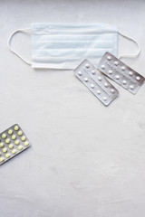 Medical mask on a gray background with pills