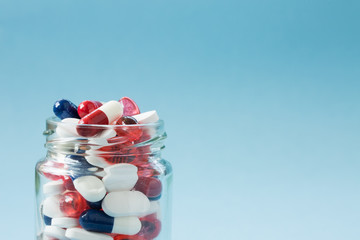 A jar full of drugs, tablets, pills, painkillers and prescription drugs in a close up, medical concept with copy space