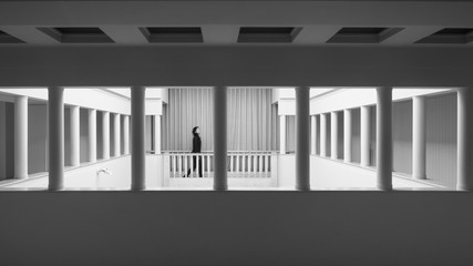 Una joven pasa andando entre las columnas de un edificio solitario