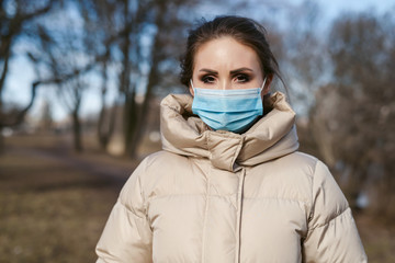 Prevention of coronavirus outbreak in 2020. Outdoor portrait of young european woman wearing a disposable facial mask. Prevent pollution and disease concept.