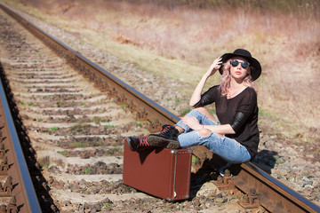 Young traveling woman with a suitcase on the railway