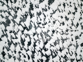 Ice of frozen lake textured by patches of snow