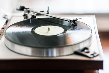Fototapeta na wymiar vinyl record turntable on wooden base playing a vinyl record