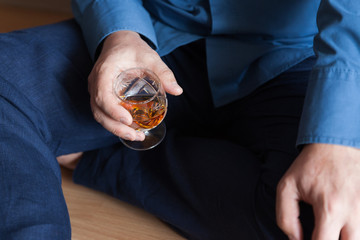 A man with a glass of brandy sits at home on the floor, the doctor after a hard shift in the...