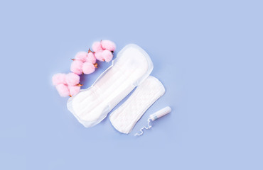 Sanitary pad on pink, cotton flowers. Personal care, woman hygiene concept.