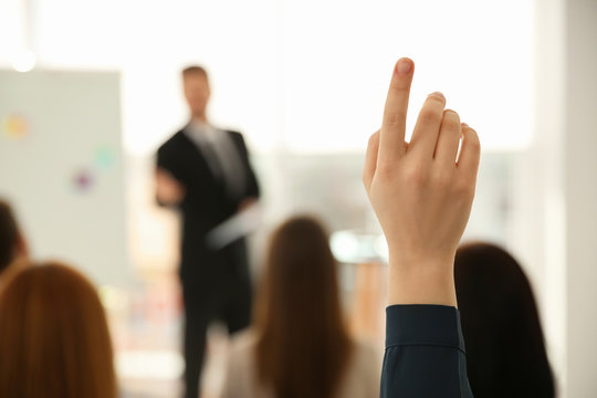 Young woman raising hand to ask question at business training indoors, closeup