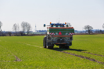 Fototapeta na wymiar Tractor spreads fertilizer on field