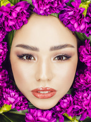 Woman with make-up and flowers around her face. Woman and flowers. Spring.