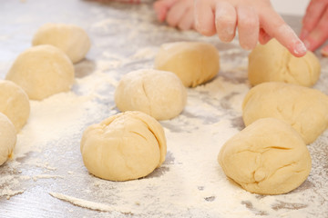 Unleavened dough for tortillas with flour and hand on kitchen table. Cooking burrito.