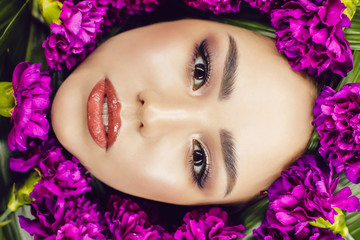 Woman with make-up and flowers around her face. Woman and flowers. Spring.