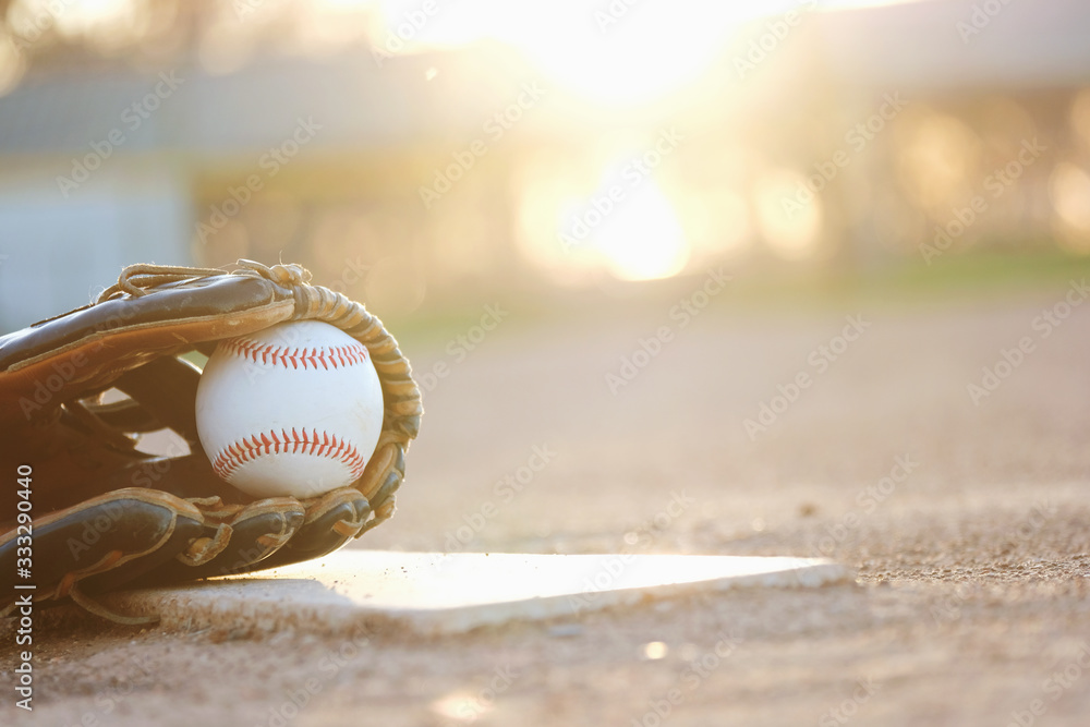 Poster baseball glove and ball on field during sunset with blurred background. - Posters