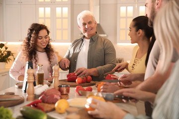 Happy people cooking food together in kitchen