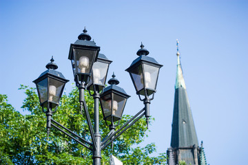 Modern energy saving lamps in an antique street lamp, with a gothic church in the background