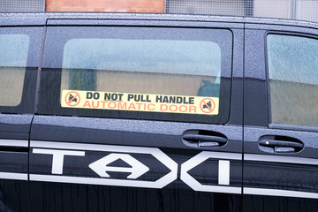 Taxi automatic door do not pull handle sign on black cab car